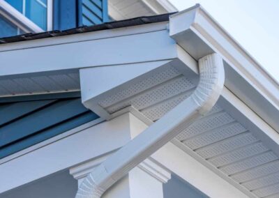 Colonial white gutter guard system, fascia, drip edge, soffit providing ventilation to the attic, with pacific blue vinyl horizontal siding at a luxury American single family home neighborhood USA